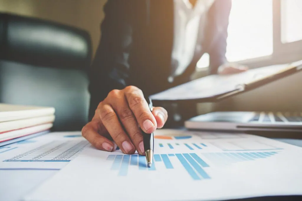 Hand pointing at business charts on desk