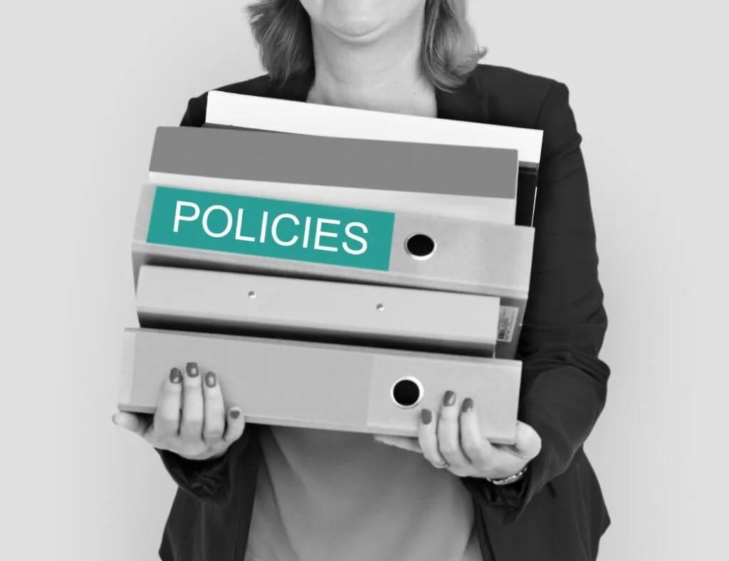 Woman holding stack of policy binders