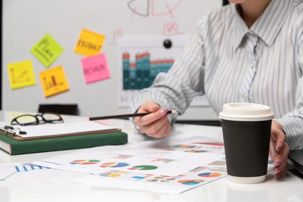 Woman working with graphs and holding coffee cup