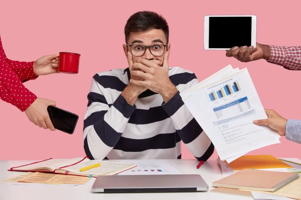 Stressed man surrounded by hands with office items
