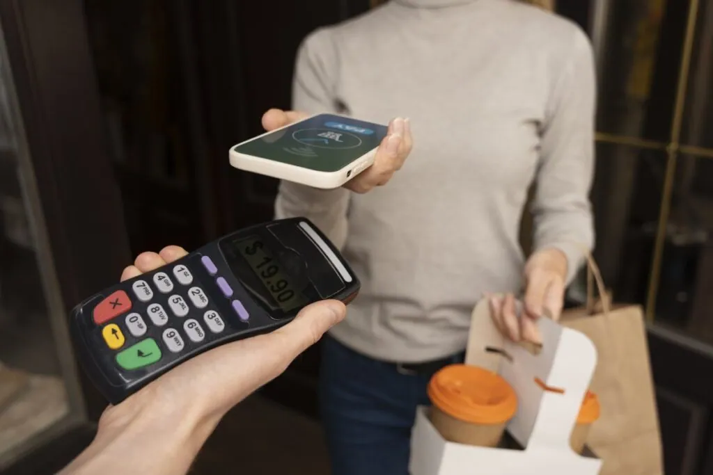 Woman paying with smartphone at cafe counter