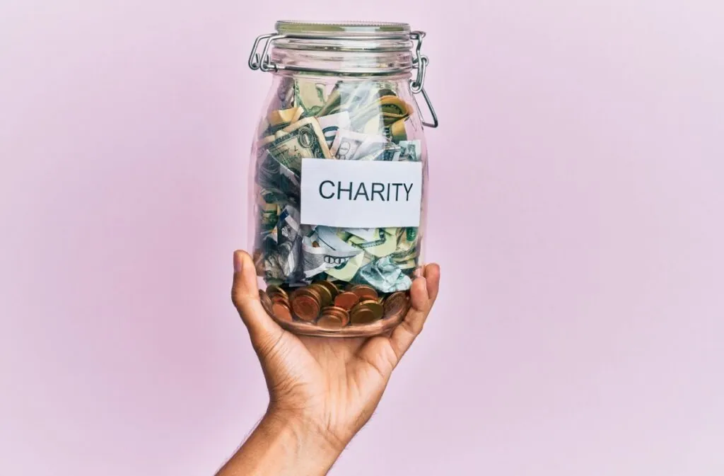 hand-hispanic-man-holding-charity-jar-with-dollars-isolated-pink-background