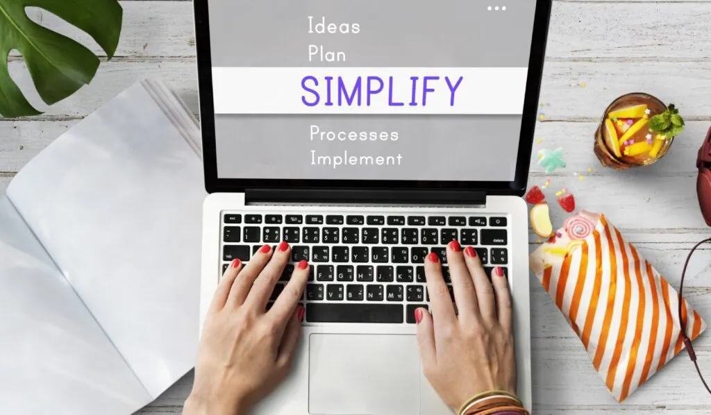 Hands typing on laptop with "Simplify" highlighted on screen