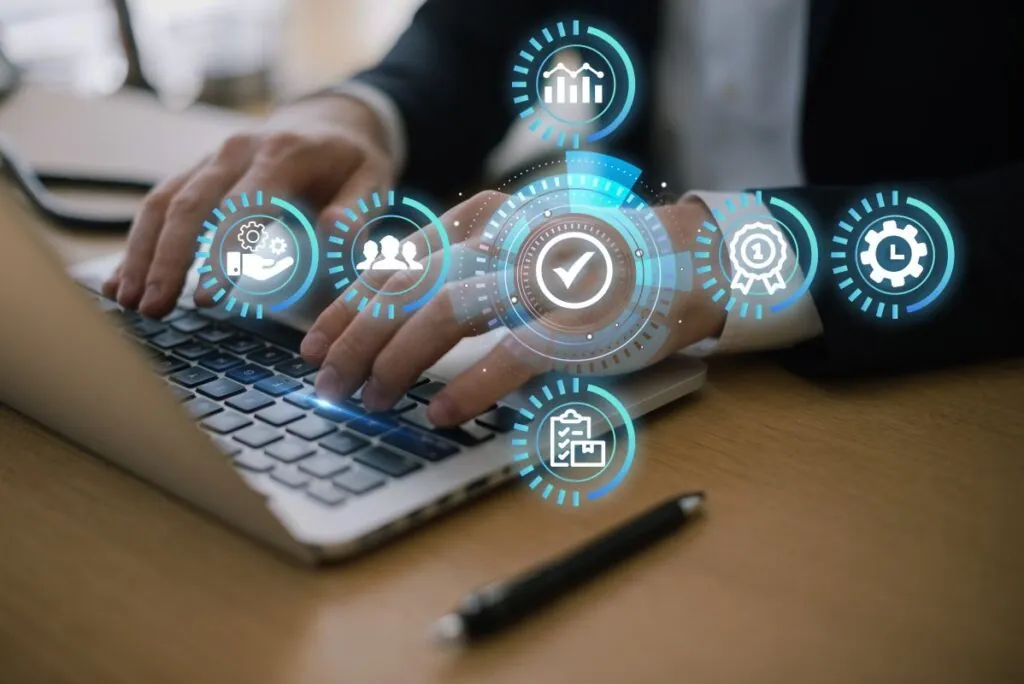 Person typing on laptop with floating digital icons