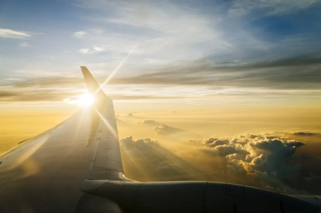 Airplane wing with sunset above the clouds