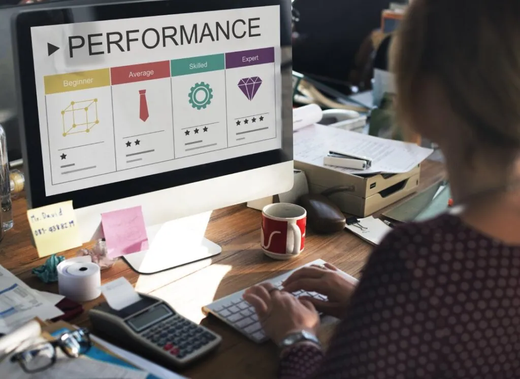 Person typing at a desk with performance chart on computer screen