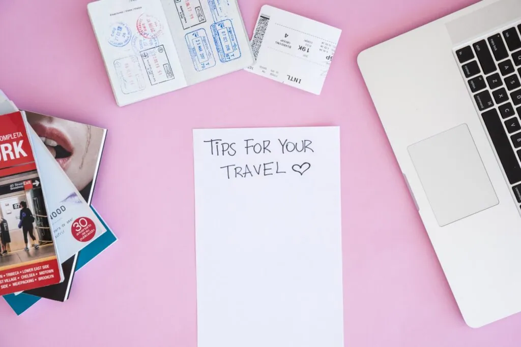 Travel tips list with passport and laptop on pink background