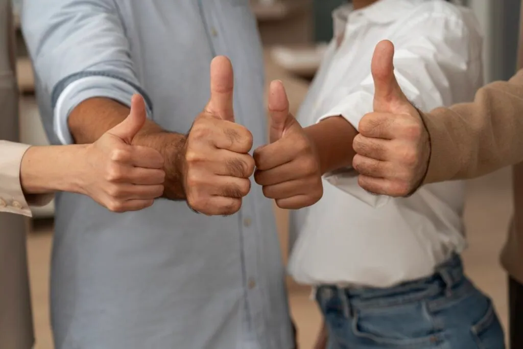 Group of people giving thumbs up together