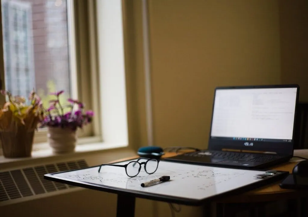 Workspace with laptop whiteboard and glasses