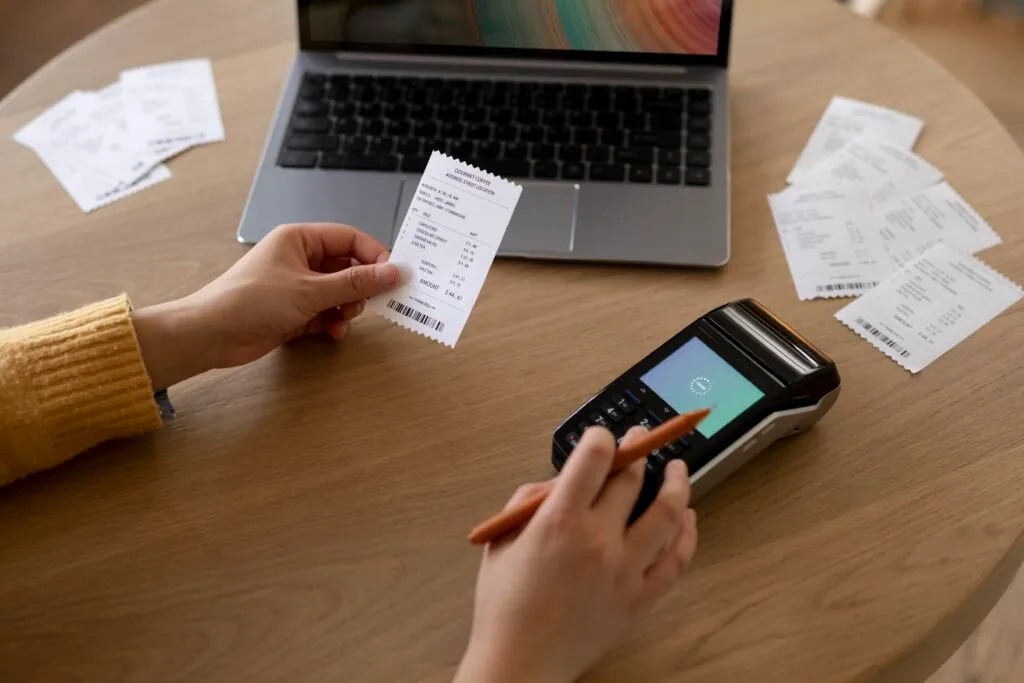 Person checking receipts with a laptop and card reader