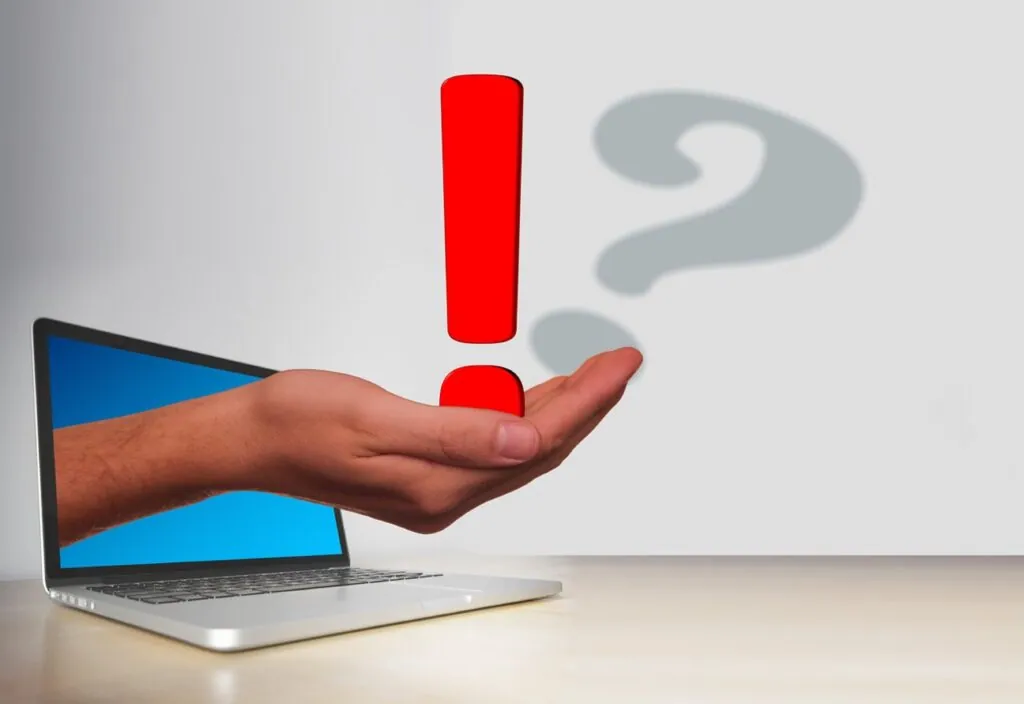 Hand emerging from laptop holding exclamation mark