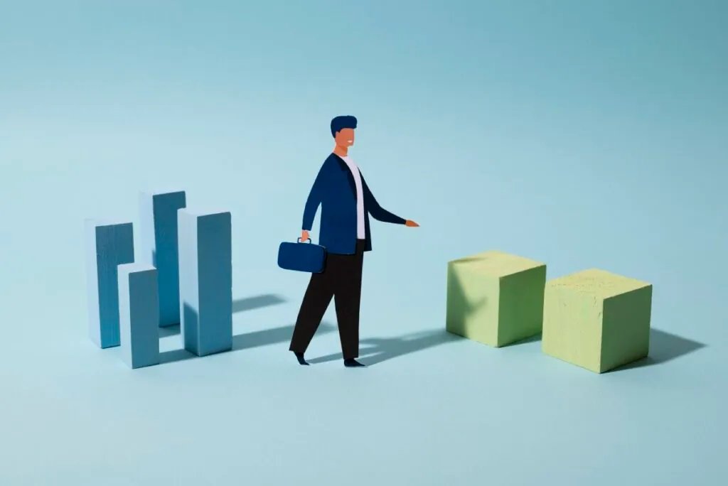 Paper cutout figure with briefcase walking between blocks