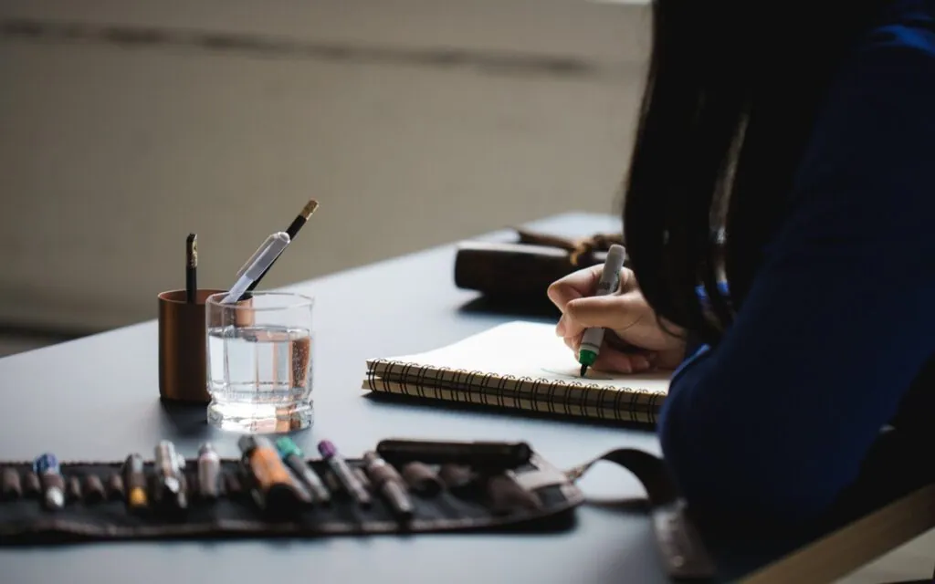 Person writing in a notebook on a desk