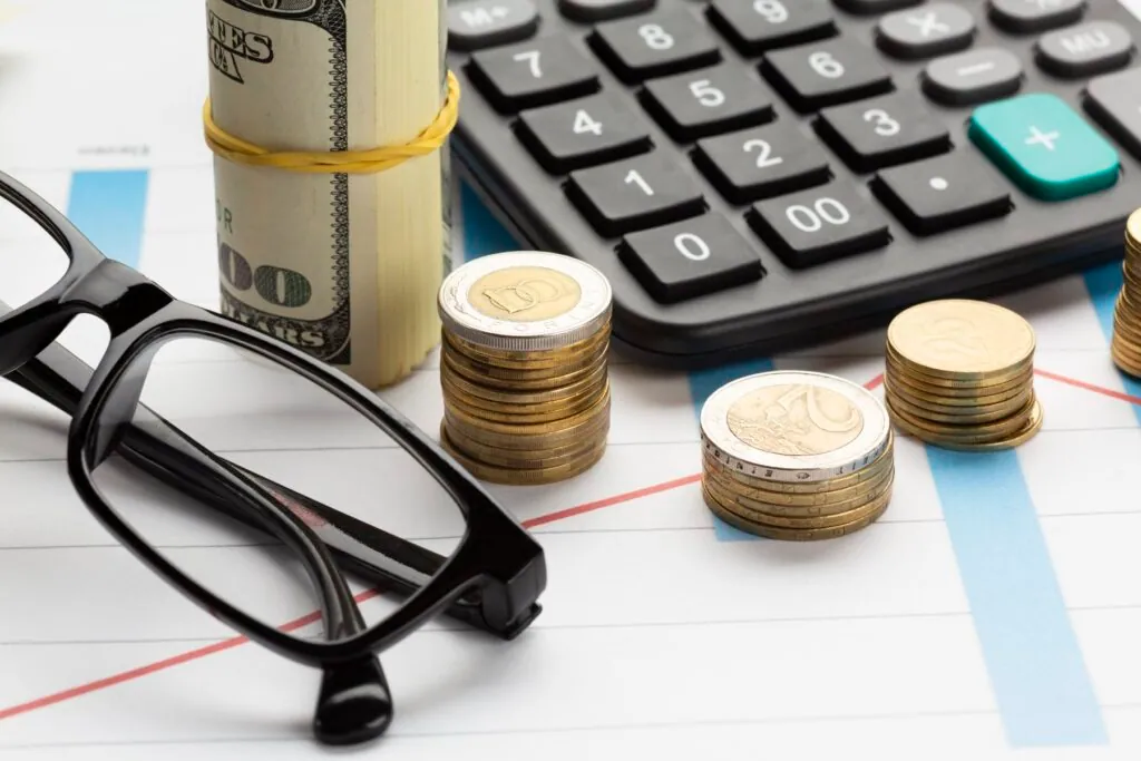 Calculator with coins glasses and dollar bills