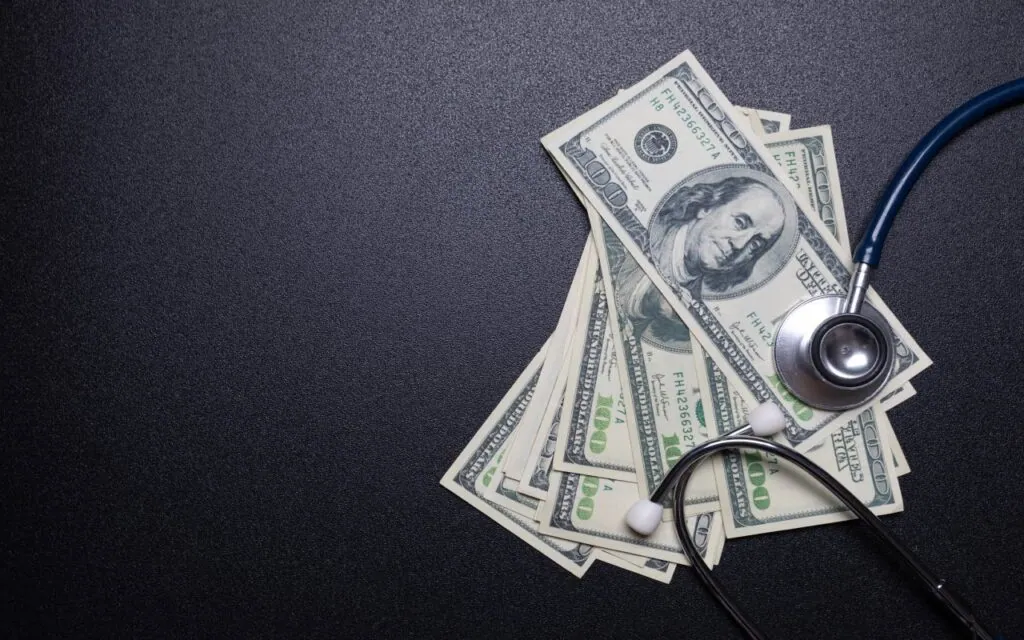 Stethoscope and dollar bills on black surface