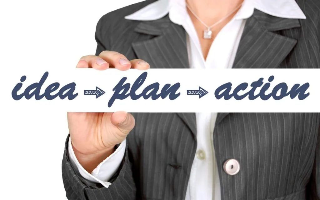 Businessperson holding "idea plan action" sign