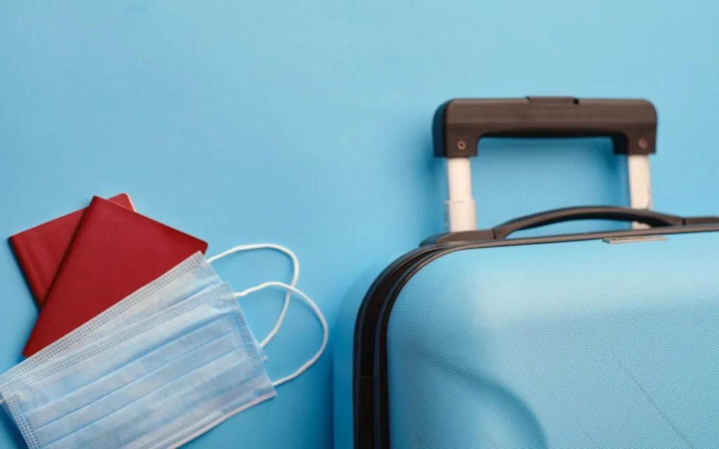 Suitcase passports and face masks on blue background