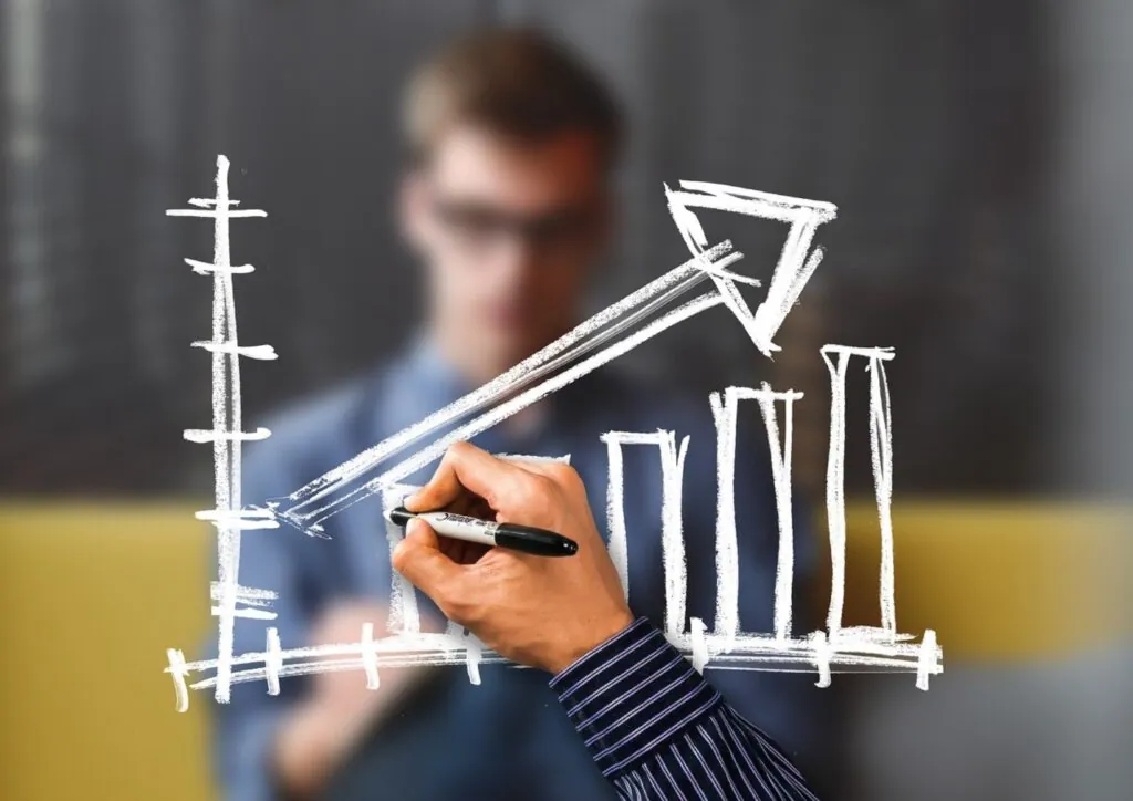 Person drawing a rising graph on a transparent board