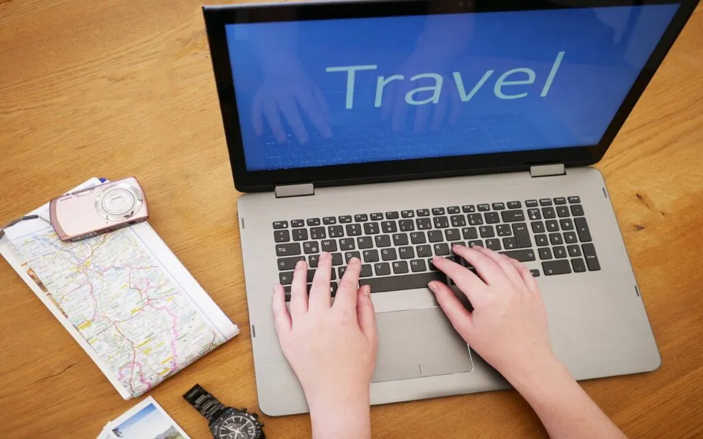 Hands typing "Travel" on laptop keyboard