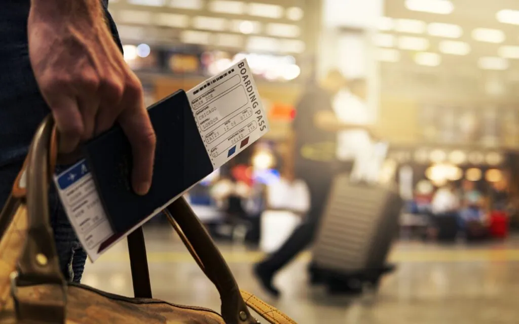 Hand holding a boarding pass and passport
