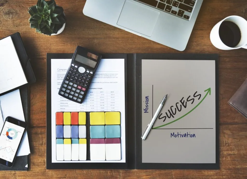Desk with laptop calculator and success chart