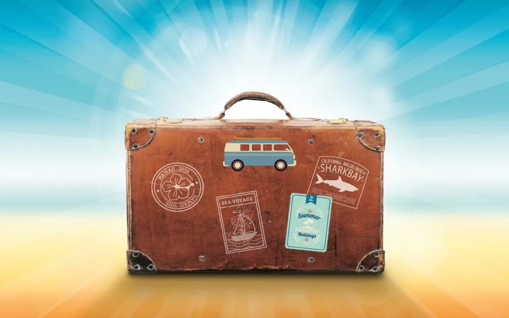 Vintage suitcase with travel stickers against bright background