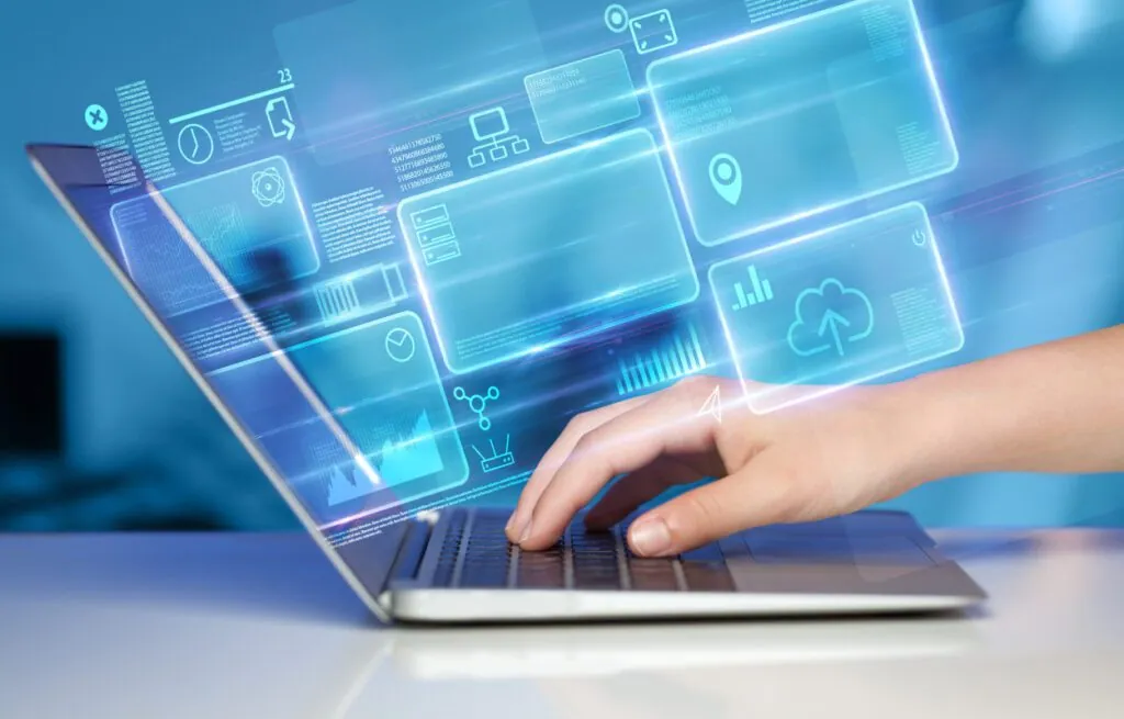 Hand typing on laptop with holographic data
