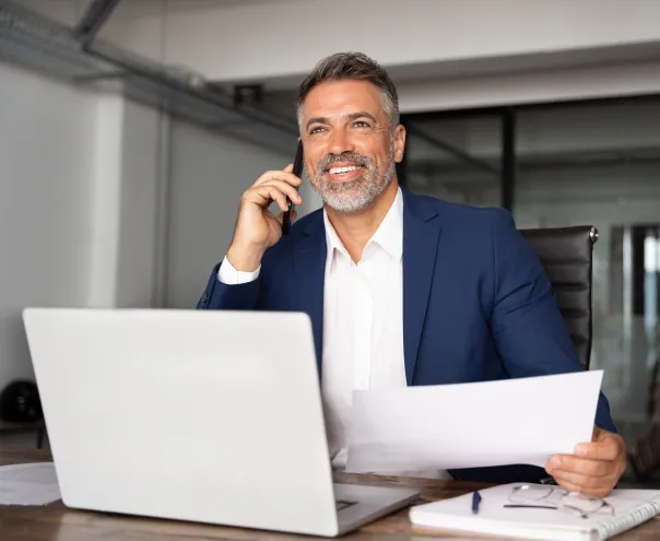 Smiling businessman talking on phone holding a paper