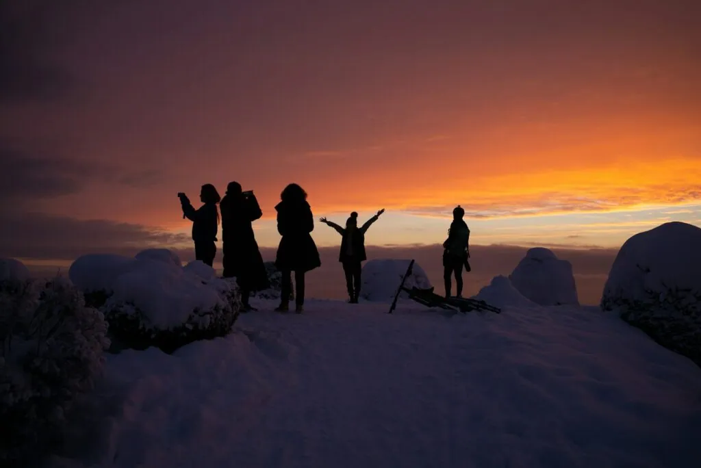 silhouette of people on snow covered ground during sunset