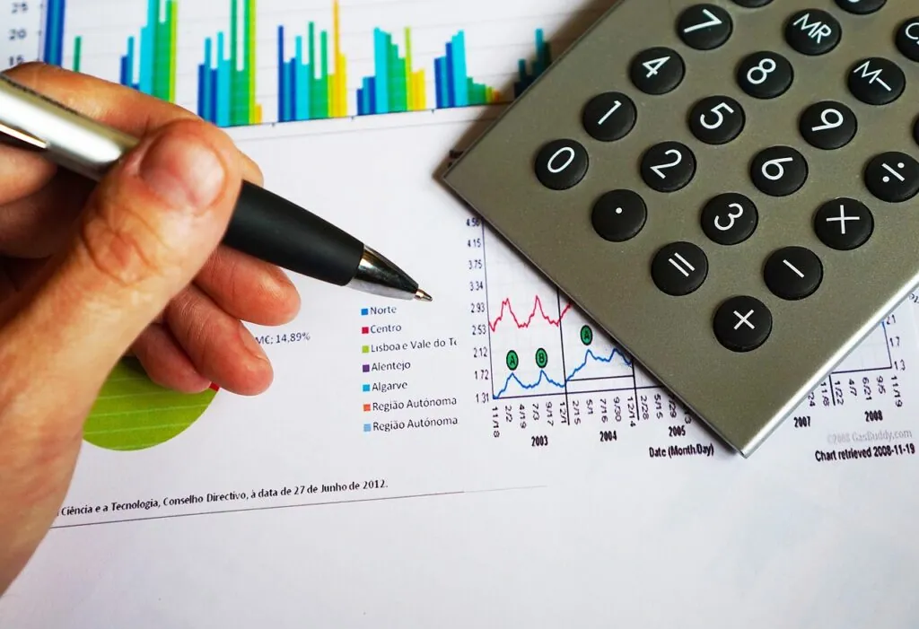 Hand holding pen near financial charts