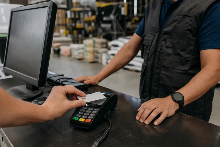 Employee corporate card being tapped at a hardware store counter, realistic photo