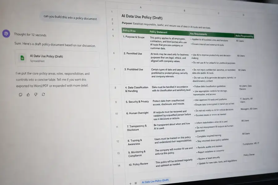 Of a screen showing a spreadsheet or policy document being built from an AI chat conversation, shallow depth of field, realistic photo