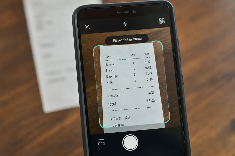 Of phone camera capturing a receipt with an app interface overlay, shallow depth of field, realistic photo