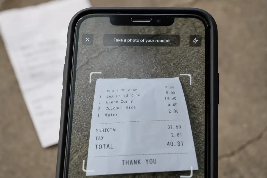 Phone camera capturing a receipt with an app interface overlay