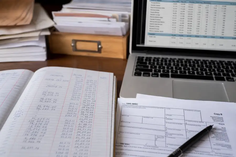 Of organized ledger and 1099 forms beside a laptop with accounting software, shallow depth of field, realistic photo