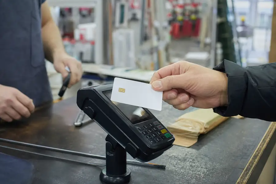 Employee corporate card being tapped at a hardware store counter, realistic photo