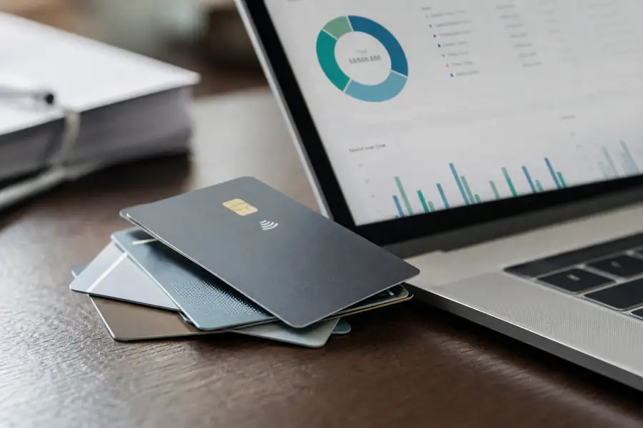 Of corporate cards laid on a desk beside a spend dashboard on a laptop, shallow depth of field, realistic photo